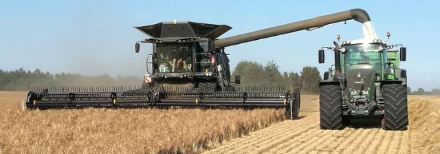 Combine harvester and tractor during harvesting of a field.